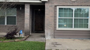 A two-story house with a front entrance, a garage door, and a small front yard. - Cute And Cozy Hostel (Houston)