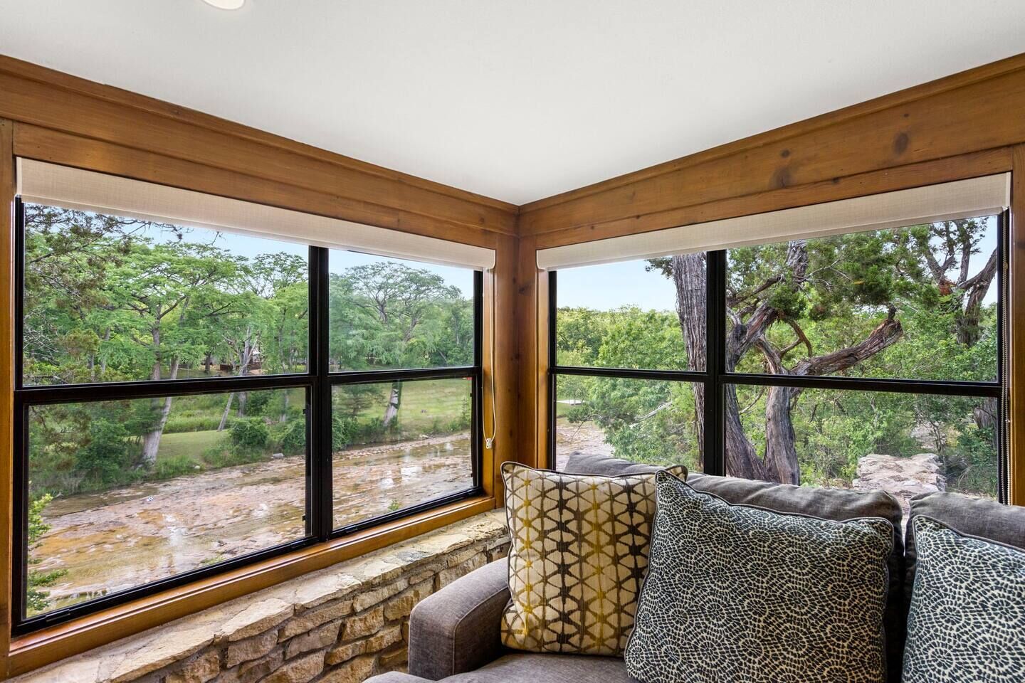 A room with large windows offering a view of a natural landscape.