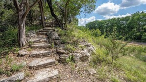 Una escalera de piedra que asciende por una colina, rodeada de árboles y vegetación.