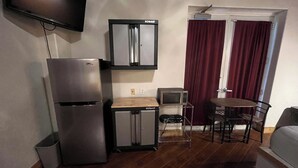 Une petite cuisine équipée comprenant un réfrigérateur, un four à micro-ondes et un coin repas avec une table et des chaises.