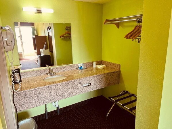 A bathroom with a granite countertop, two sinks, a towel rack, and a mirror.