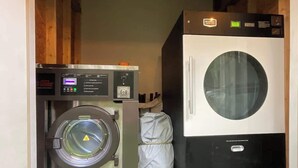 A compact laundry room with a front-loading washing machine and a stacked dryer. - Comfy Hideaway: Walk to Restaurants and Nightlife (Houston)