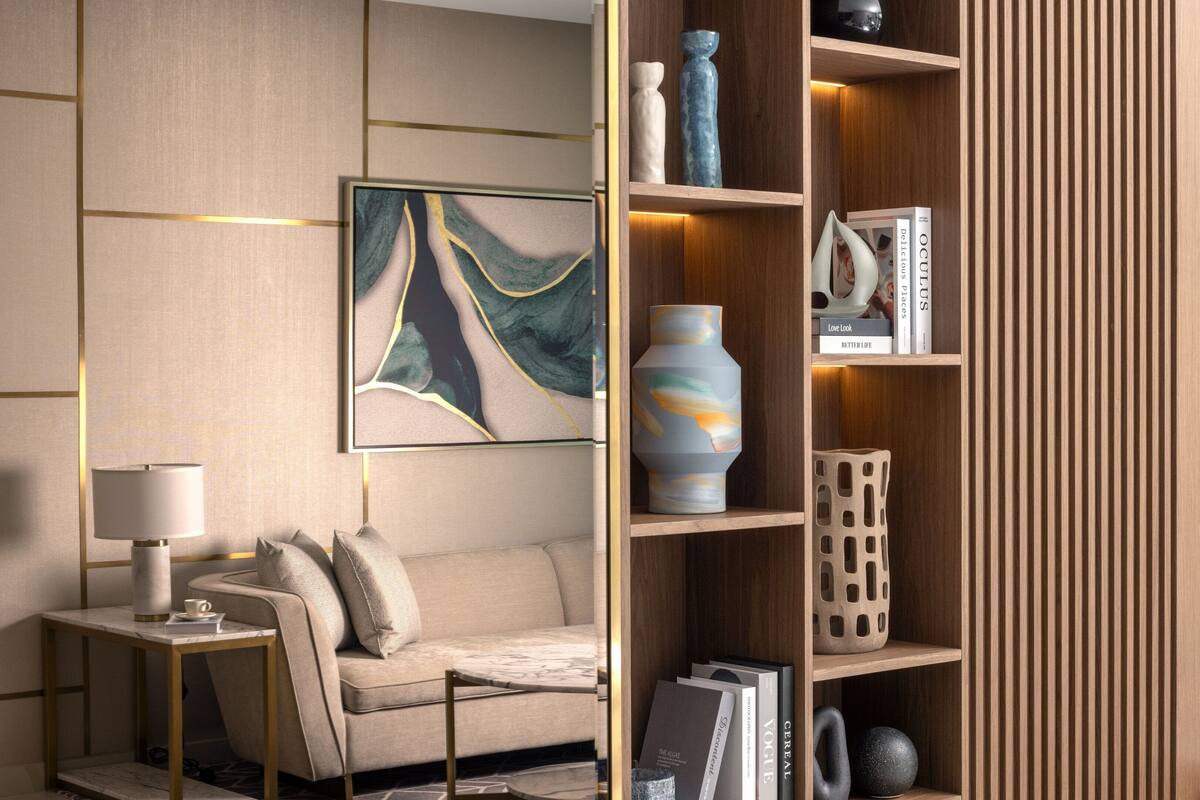 Een moderne woonkamer met een bank, een salontafel, een bijzettafeltje met een lamp, een boekenkast met decoratieve objecten en een groot abstract schilderij.