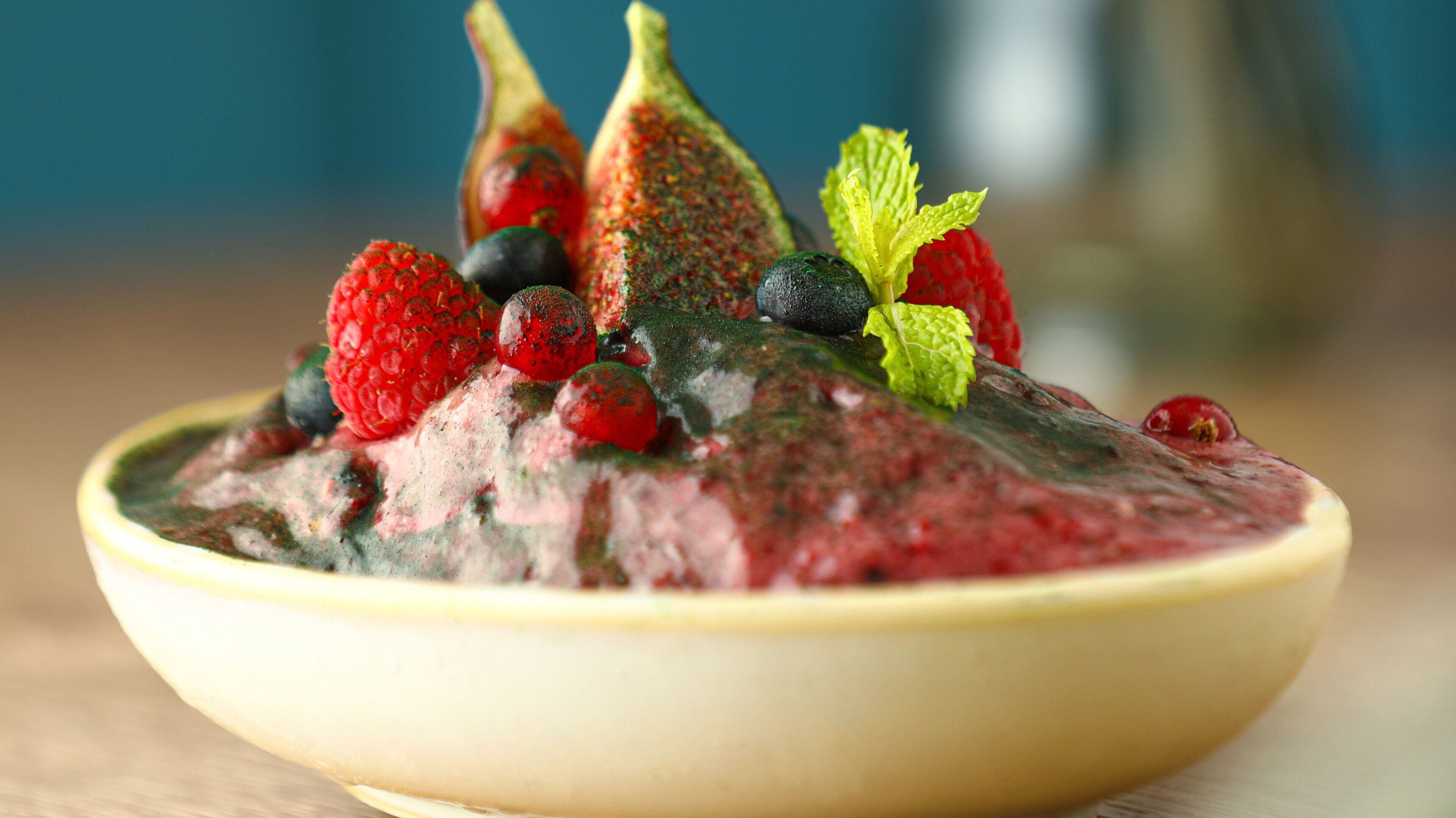 Un saladier rempli d’une salade de fruits contenant des fraises, des myrtilles et des figues.