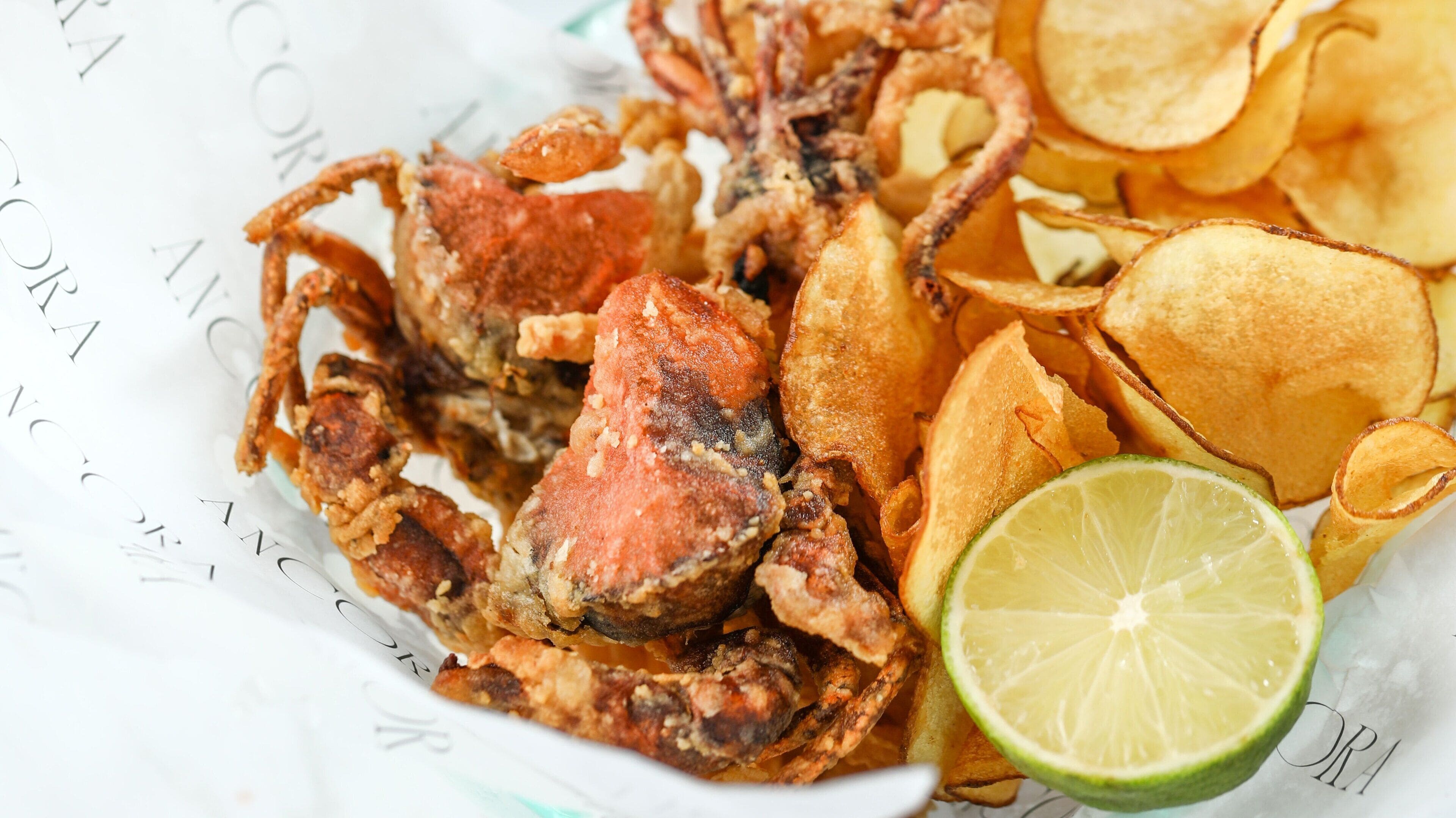 A plate of fried crab, chips, and a lime wedge.