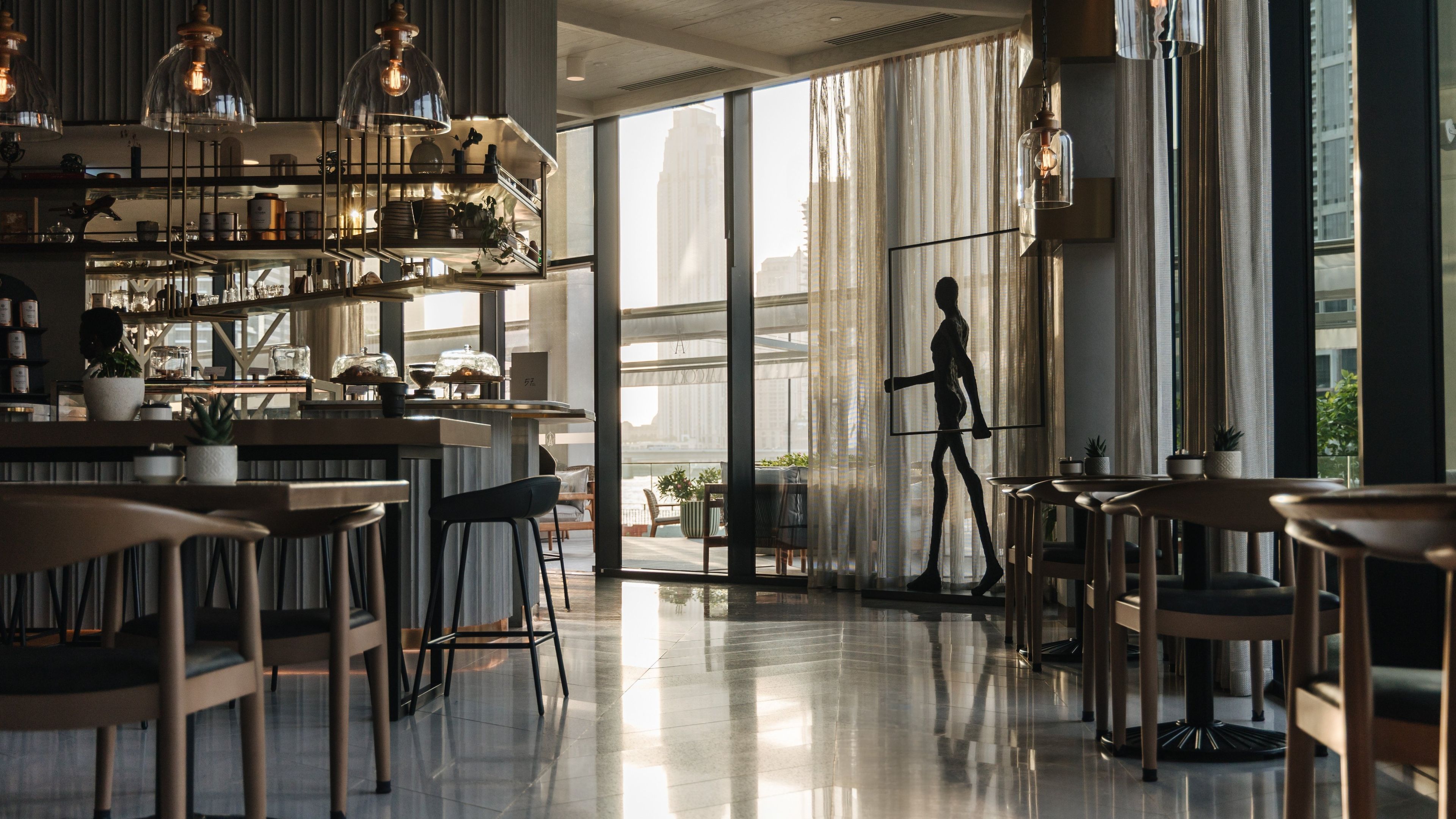 A modern interior with a bar area, seating, and large windows.