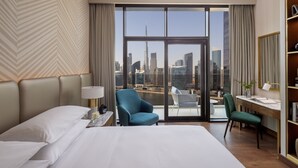 A hotel room with a large bed, two chairs, a desk, and a view of the city skyline. - InterContinental Residences Dubai Business Bay by IHG (Dubai)