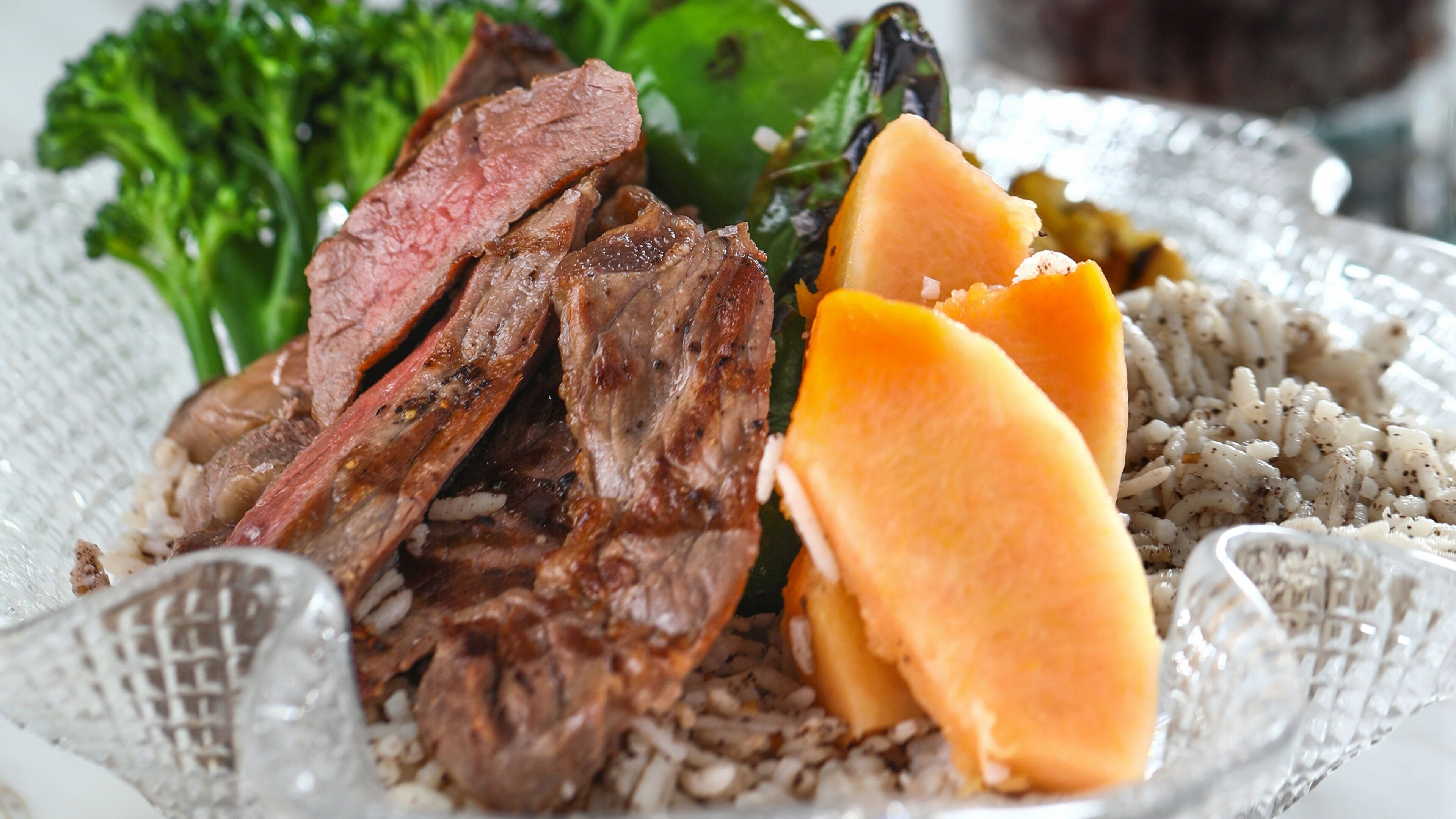 A plate with sliced beef, rice, and a piece of squash.