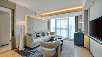 A modern living room with a sofa, a coffee table, a TV, and a large window.