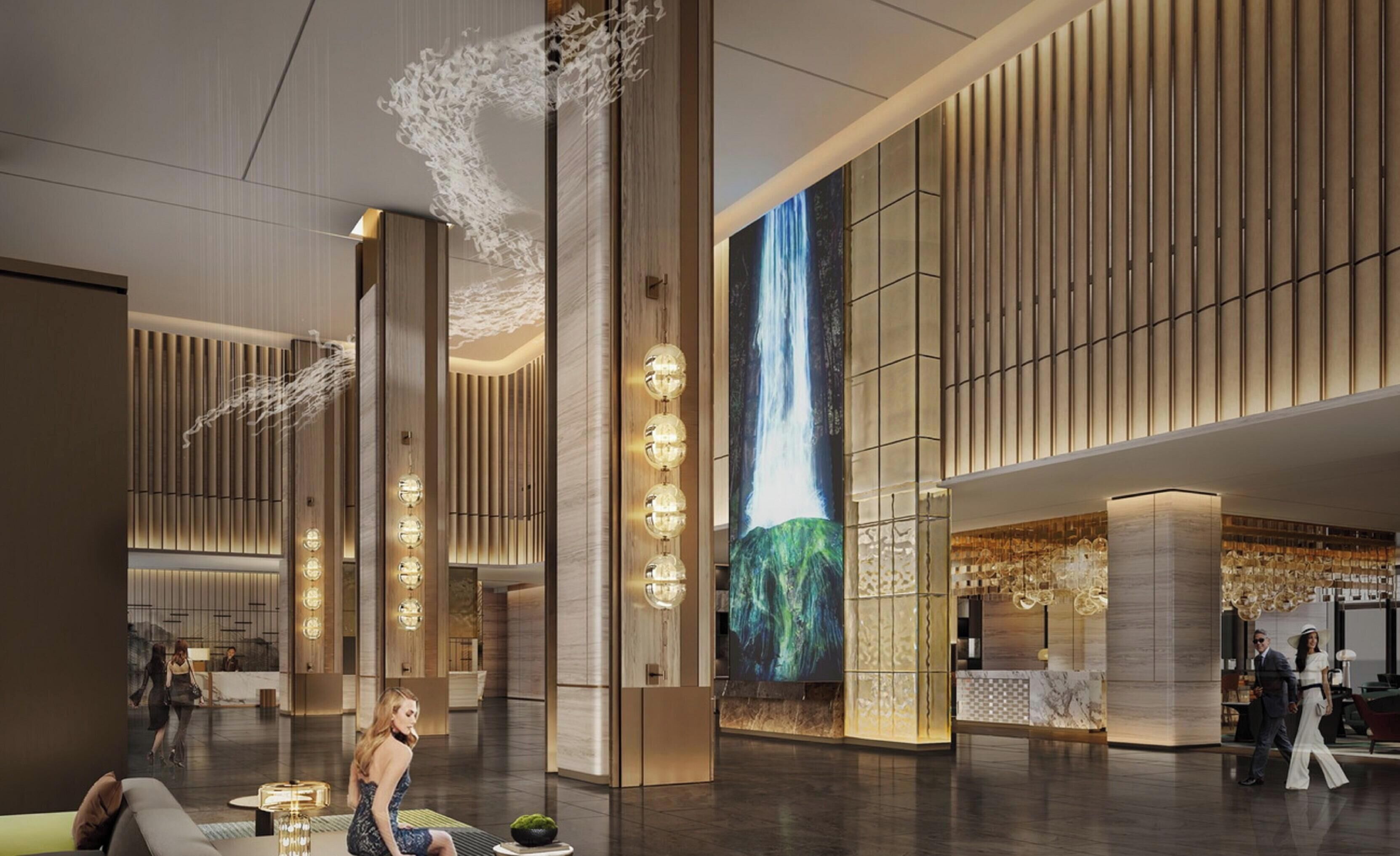 A spacious lobby with high ceilings, modern lighting fixtures, and a large digital waterfall display.