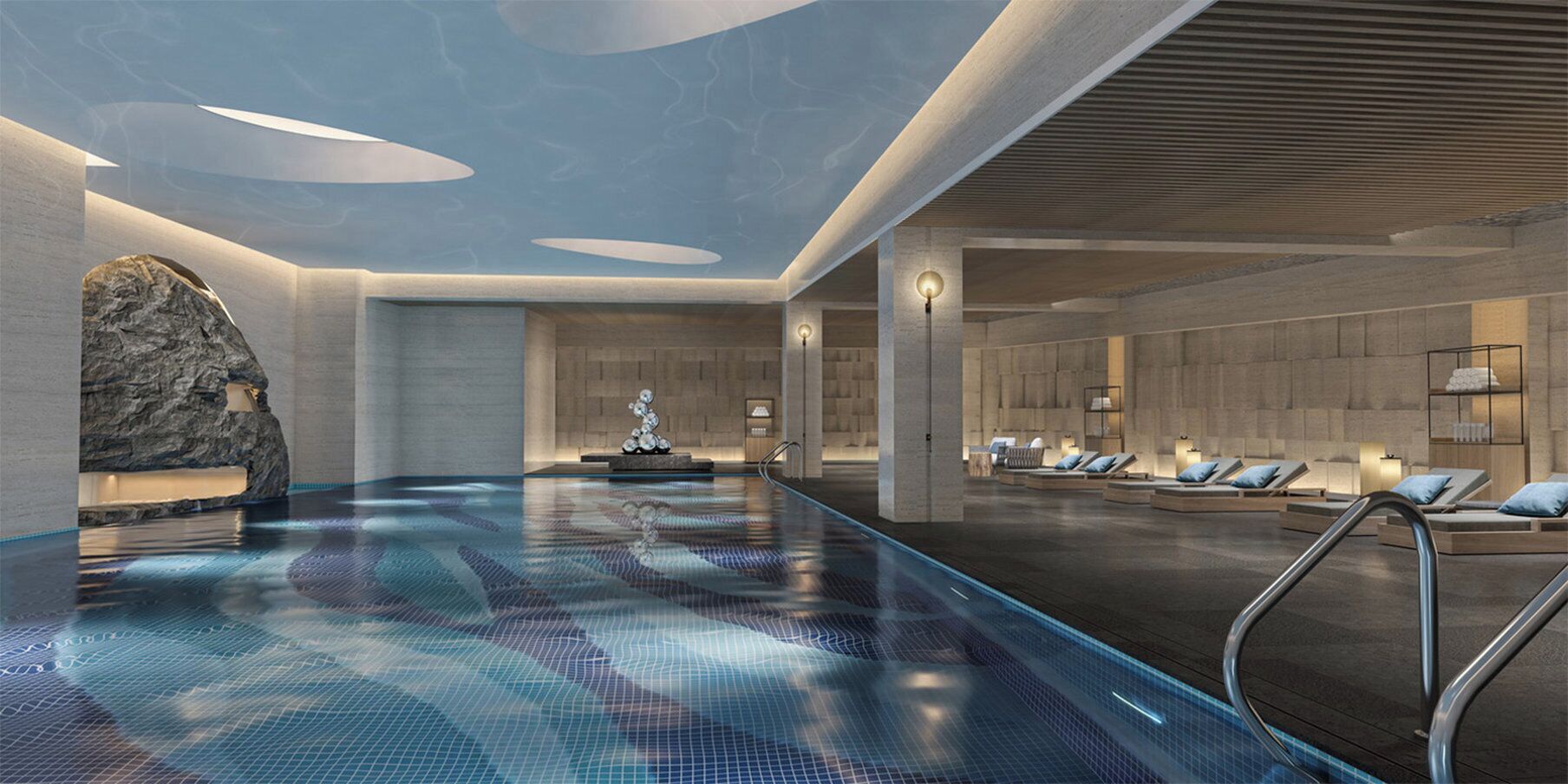 Un área interior de piscina moderna con un elemento central de agua, sillas de descanso y una pared de piedra.