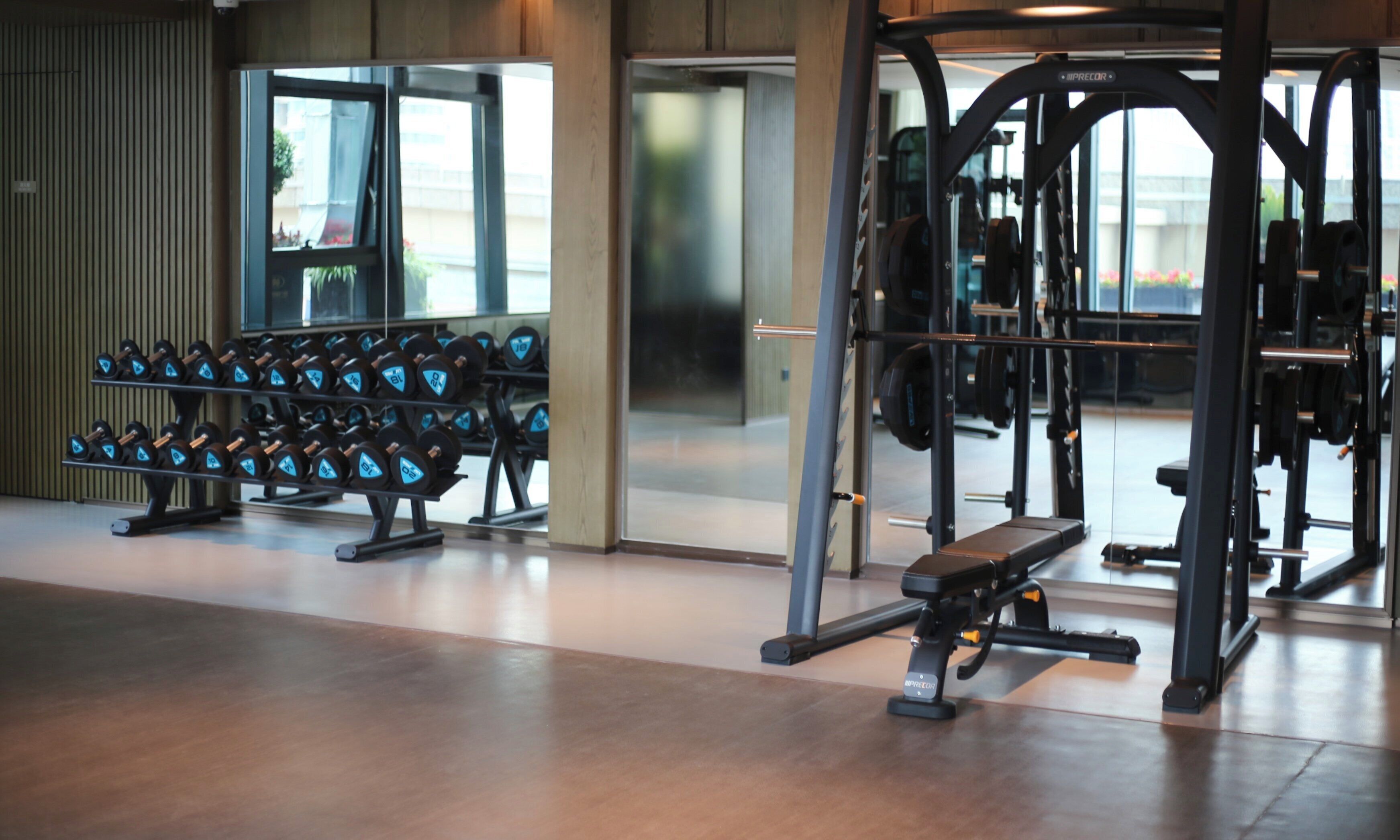 A gym with weightlifting equipment, including dumbbells and a bench press.