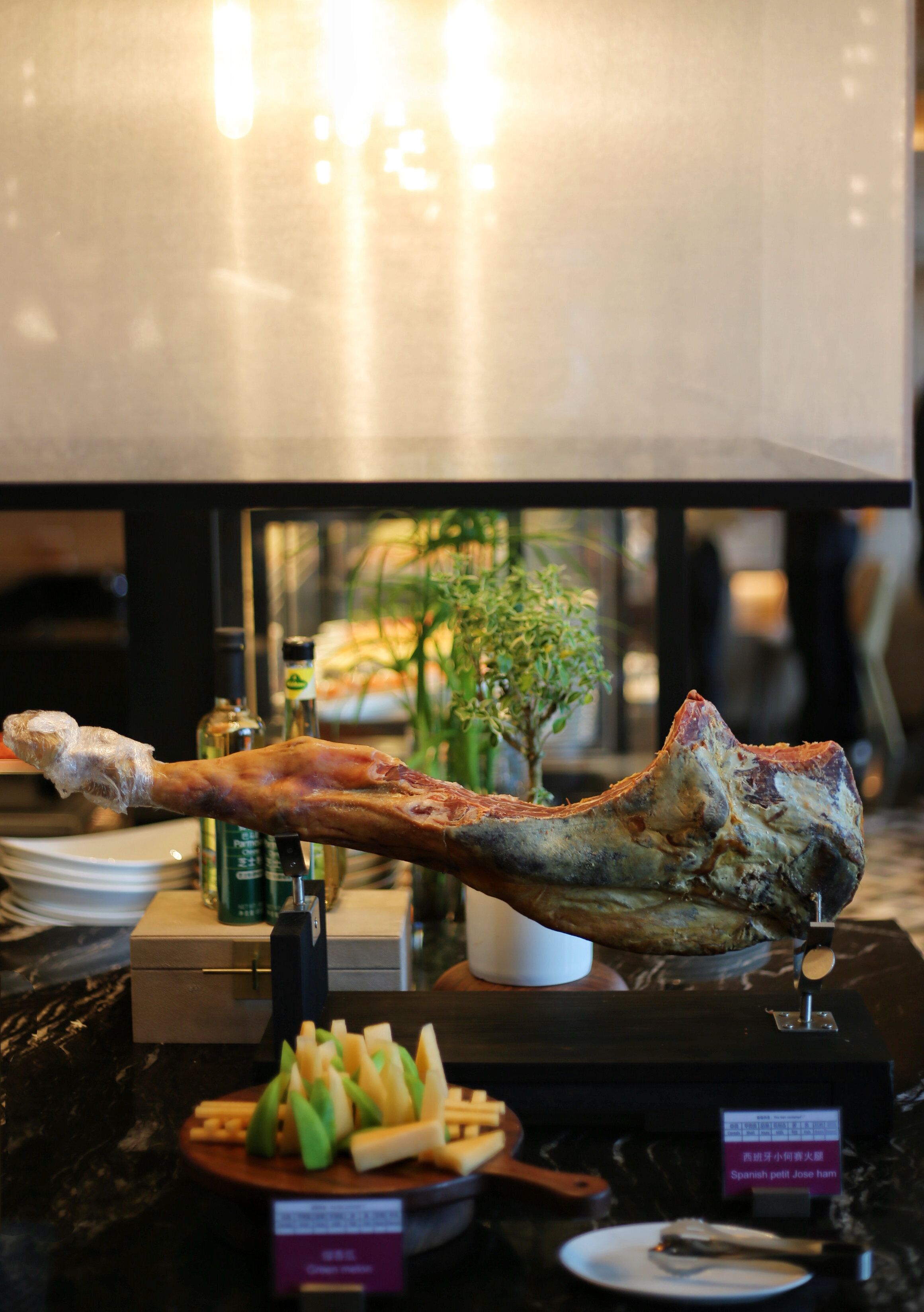 A dining table with a roasted leg of lamb, a small potted plant, and a plate of fries.
