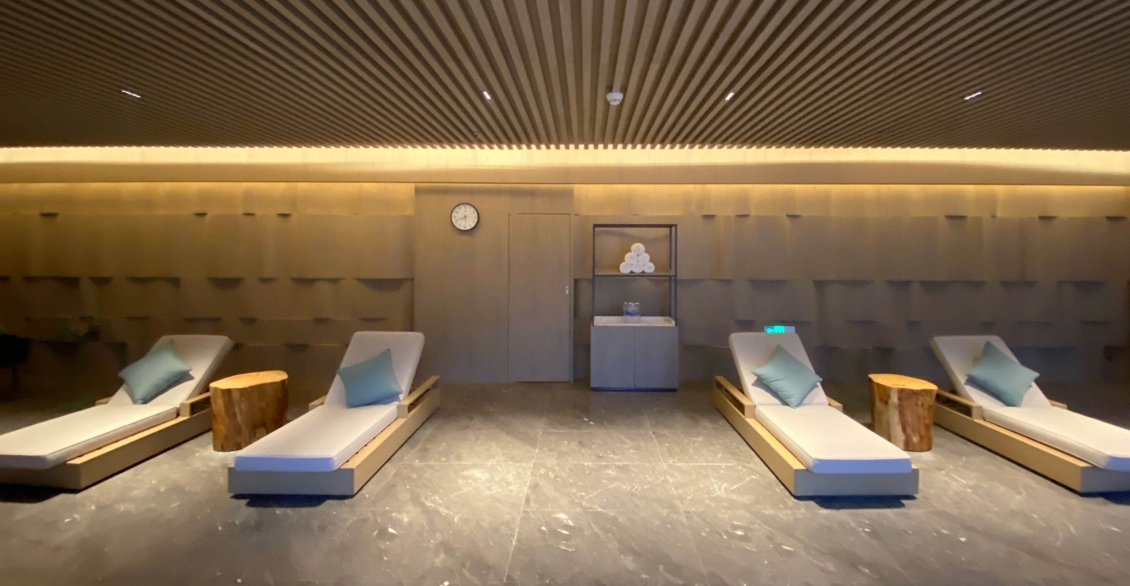 Un cuarto de spa con cuatro sillones reclinables, un reloj y un estante pequeño con un objeto decorativo.