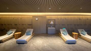 Un cuarto de spa con cuatro sillones reclinables, un reloj y un estante pequeño con un objeto decorativo.
