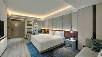 Una habitación de hotel moderna con una cama grande, mesitas de noche, un escritorio y un televisor.