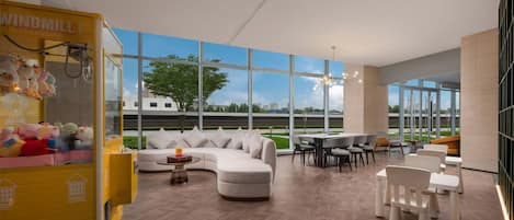 Een moderne hotellobby met een groot raamzicht, een comfortabele bank, een eetgedeelte en een kinderspeelruimte met molenthema.