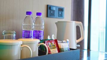 Ett hotellrum med en frukosthörna som innehåller en kaffebryggare, två vattenflaskor, en mugg, en förpackning te och en glasburk.