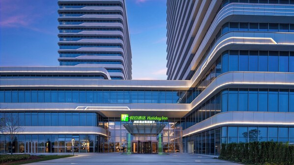 Ett modernt hotell med en fasad av glas, en framträdande entré och en skylt som visar att det är ett Holiday Inn.