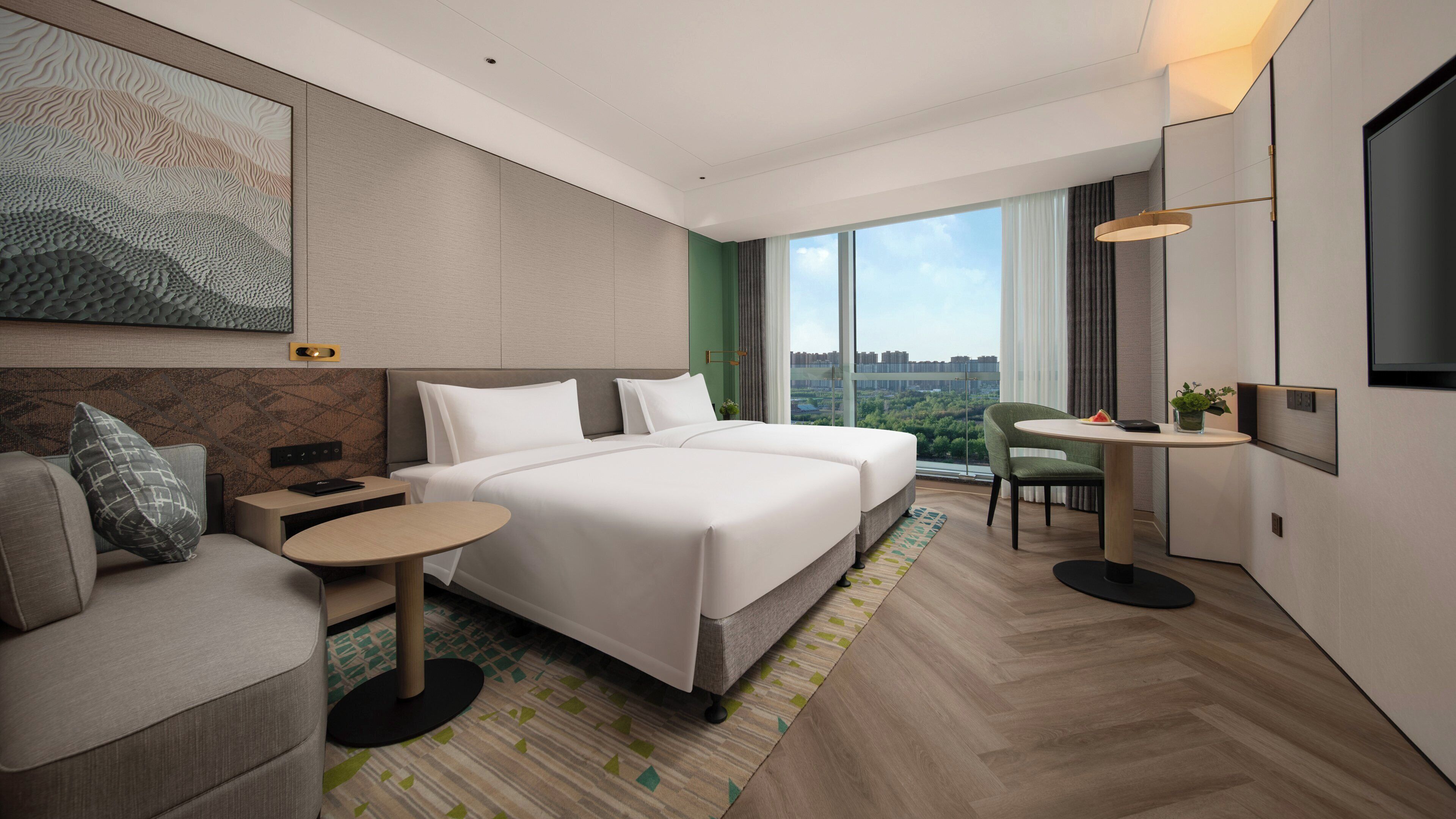 A modern hotel room with a large bed, a sofa, a small table, and a TV.
