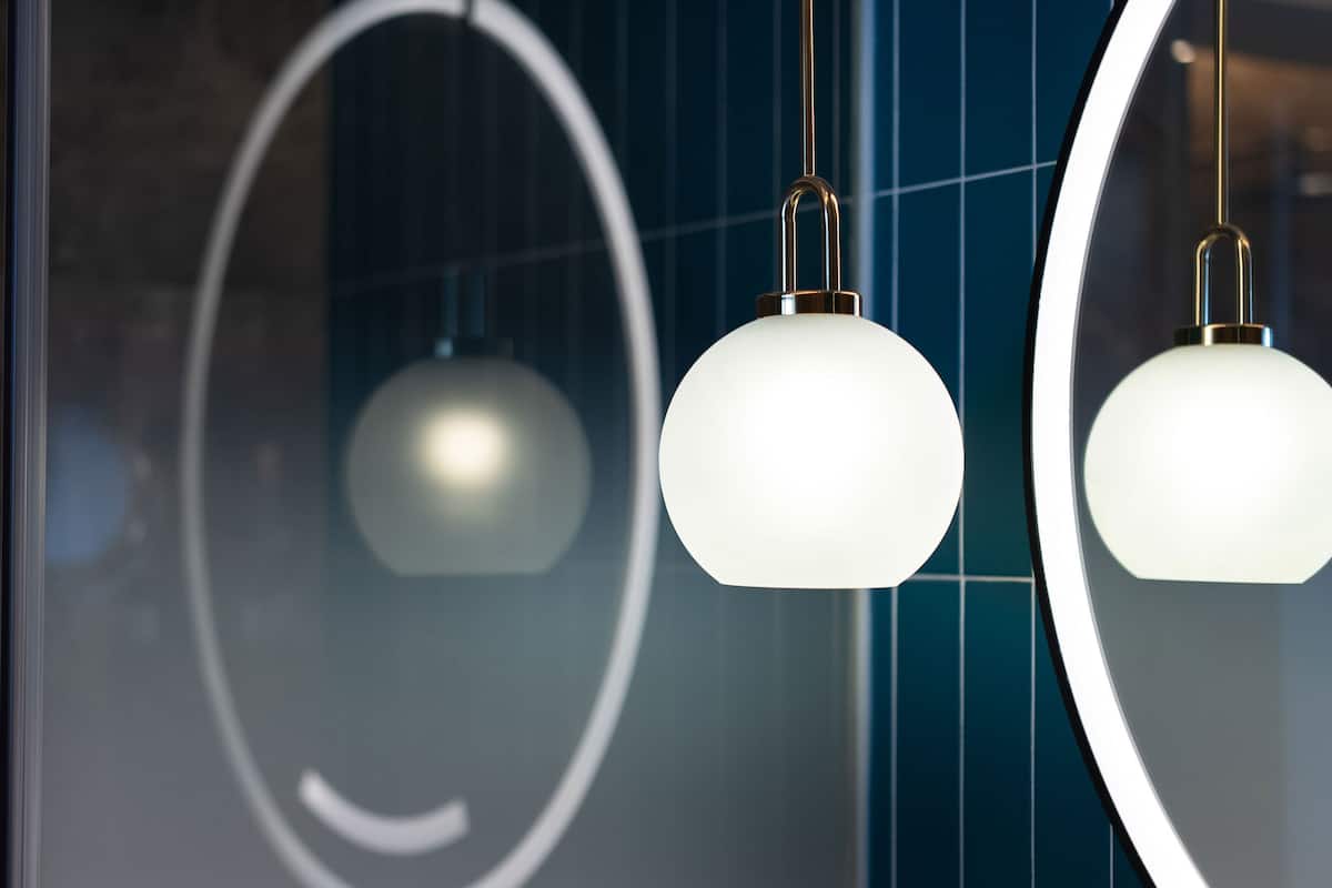 A modern interior with two spherical pendant lights and a large mirror reflecting a geometric design.