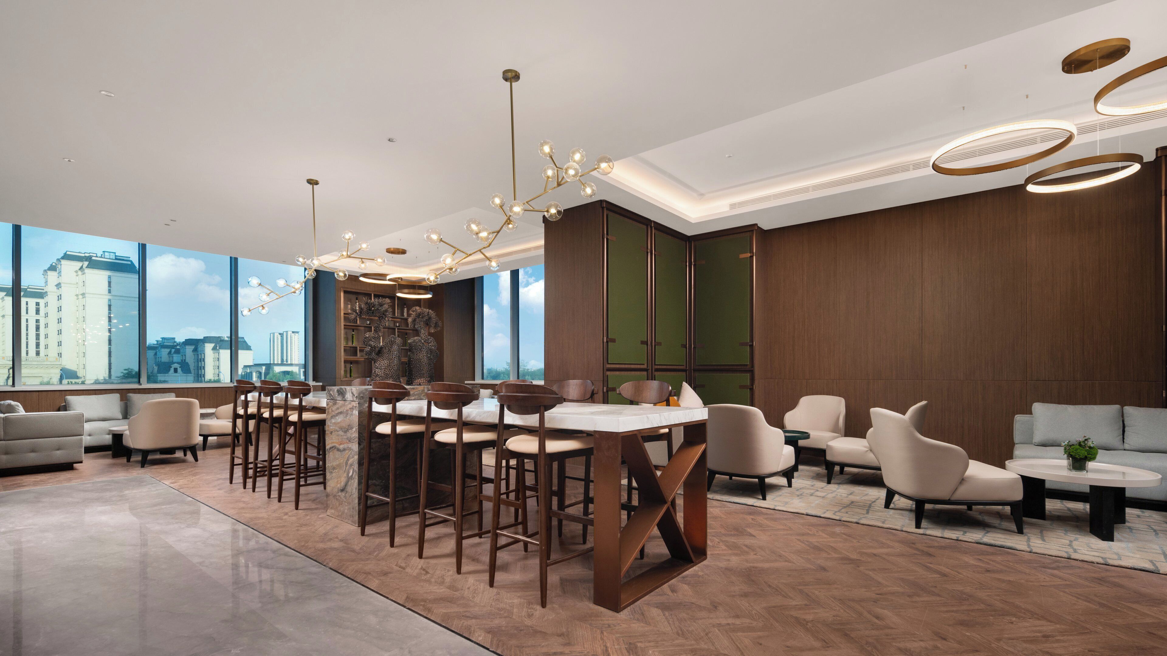 A modern hotel lobby with a bar area, seating, and large windows offering city views.