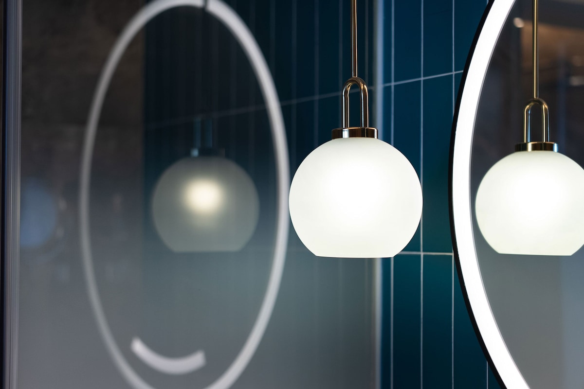 A modern interior with pendant lights and a large mirror reflecting a geometric design.