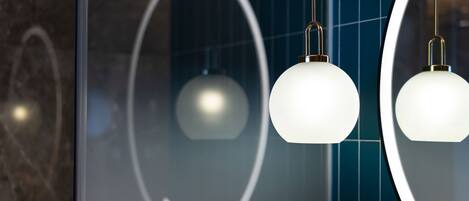 A modern interior with pendant lights and a large mirror reflecting a geometric design.