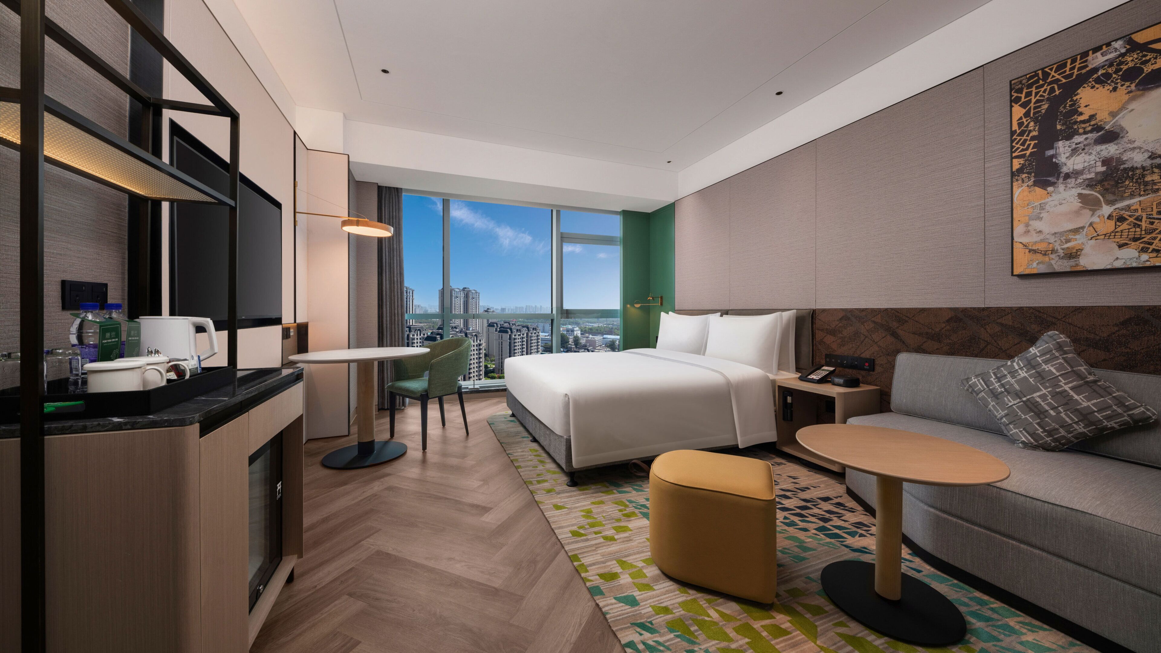 Una habitación de hotel moderna con cama, sofá, mesa de comedor y kitchenette.