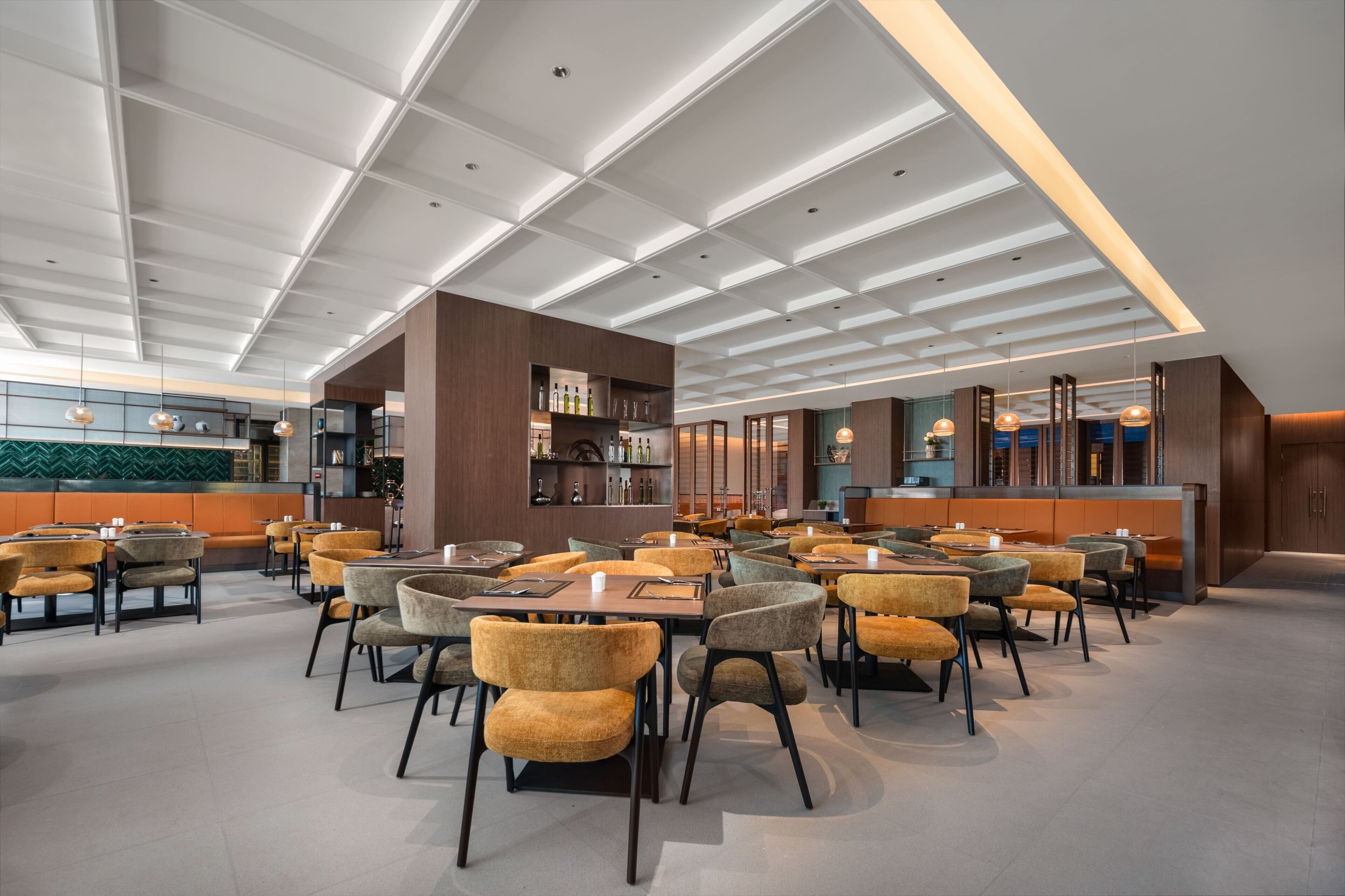A spacious restaurant with high ceilings, modern lighting, and a variety of seating arrangements.