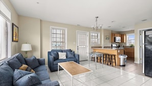 A modern kitchen with a central island, a dining area with a table and chairs, and a living room with a sofa and a coffee table. - OCHG Beachviews (Ocean City)