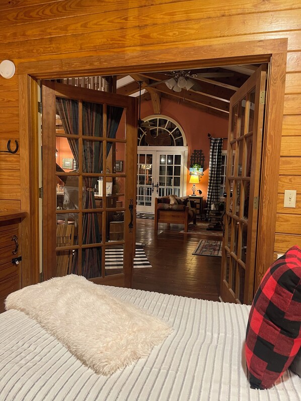 A wooden room with a bed, a fireplace, and a view of the living area.