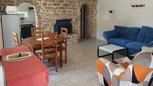 A cozy living room with a stone fireplace, a dining area with a red table, and a blue sofa. - Real Fisherman's house, Close to beach, port and windsurfing (Penmarc'h)