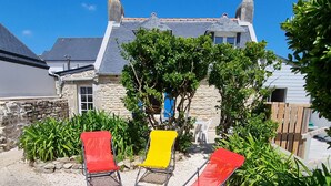 A patio with three lounge chairs, a stone wall, and a house with a grey roof. - Real Fisherman's house, Close to beach, port and windsurfing (Penmarc'h)