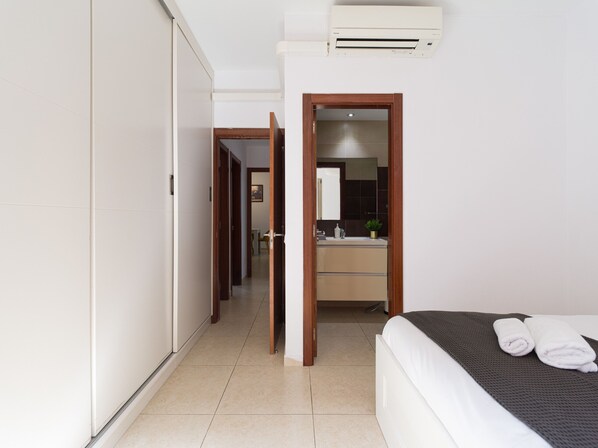 A hotel room with a bed, a bathroom with a sink and mirror, and a wardrobe.