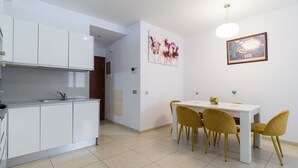 Una cocina moderna con armarios blancos y un comedor con una mesa blanca y sillas amarillas.