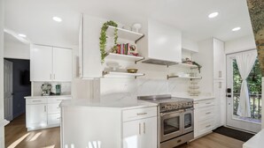 Una cocina moderna con armarios blancos, una isla central y hornos empotrados.