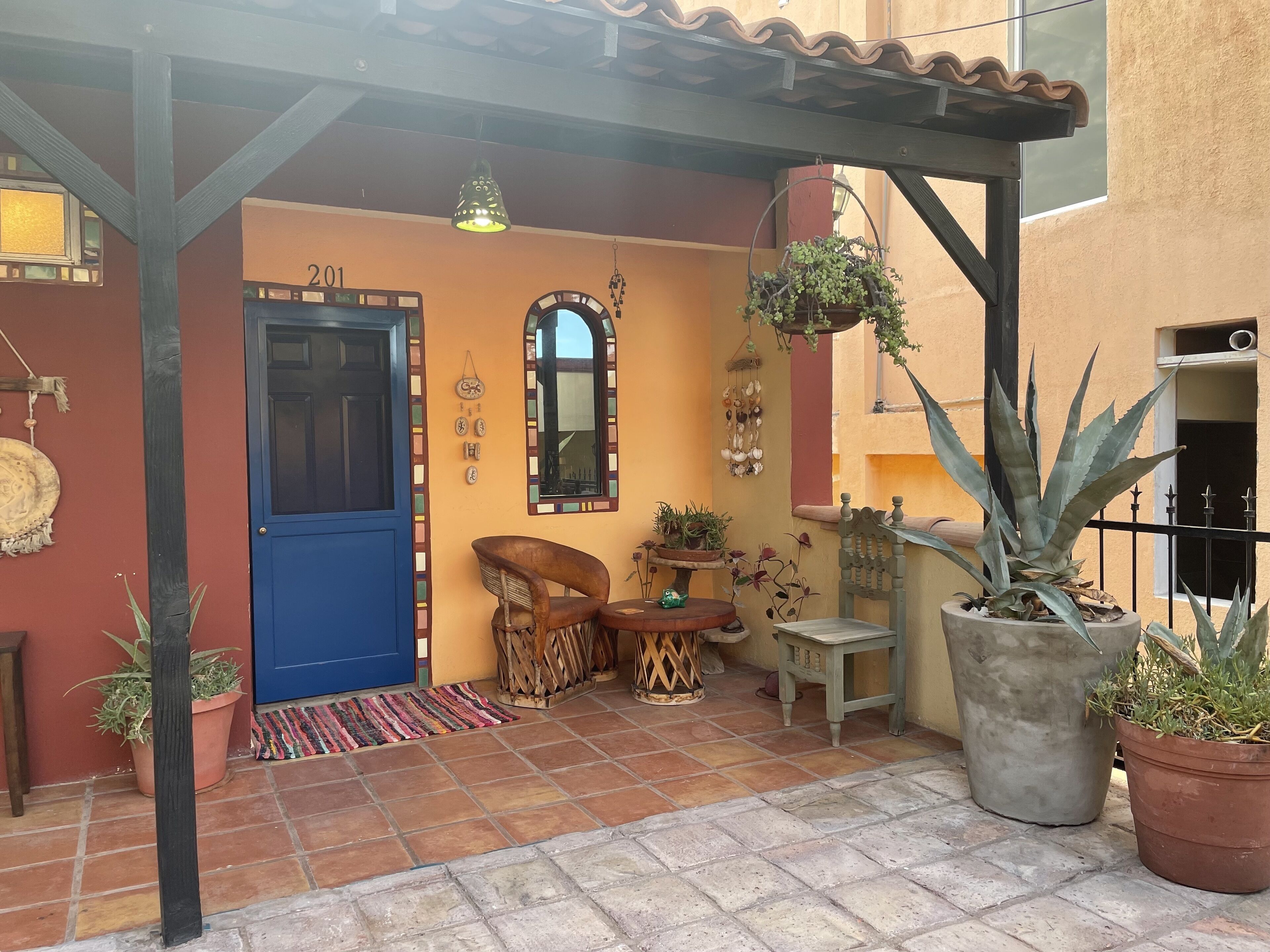 A cozy outdoor seating area with a blue door, a small table, and potted plants.