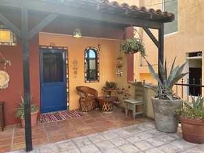 Un espace extérieur accueillant avec une porte bleue, une petite table et des plantes en pot.