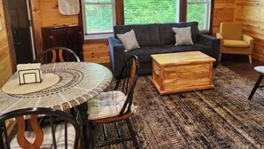 L’intérieur chaleureux d’un chalet, avec un décor en bois, un canapé, une table basse et une table à manger avec des chaises.