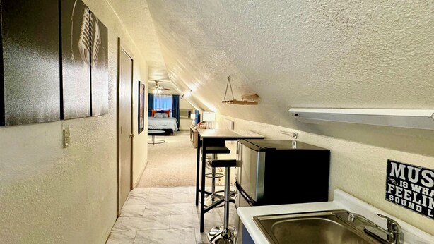 A compact hotel room with a kitchenette, a bed, and a bathroom.