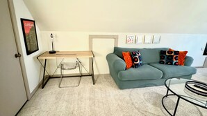 A room with a desk, a sofa, and a glass table.