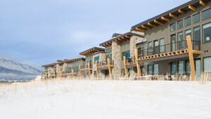 A row of modern buildings with large windows and wooden balconies, set against a snowy landscape with mountains in the background. - Adventure Awaits at R202 | Ridge Haven in Eden, UT! (Eden)