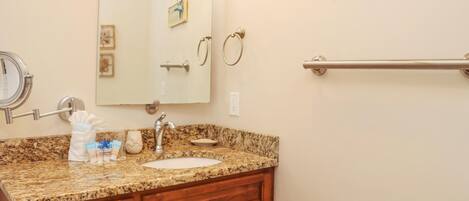 A bathroom with a granite countertop, a sink, a mirror, and a towel rack. There is a sign on the wall that says "Every day be a BEACH day."