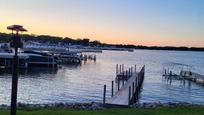 A marina with boats docked, a grassy area with a blue bench, and a clear sky. - Cozy Lake Front Cabin - East Lake Private Dock - GREAT LOCATION Next to The Ritz (Arnolds Park)