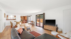 Een moderne woonkamer met een bank, televisie en een eethoek.