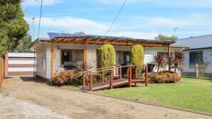Une maison de plain-pied dotée d’un porche abrité, d’un barbecue et d’une pelouse bien entretenue.