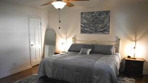 Une chambre à coucher avec un lit, un ventilateur de plafond, une lampe fixée au mur et une porte.