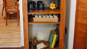 Une étagère en bois contenant divers objets de cuisine, notamment une machine à café, des tasses et une théière.