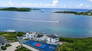 A beachfront property with a tennis court, a swimming pool, and a view of the ocean and islands. - Luxury Villa in Cabrita Point- Sky View Villa with Pickleball & Basketball Court (ST THOMAS)